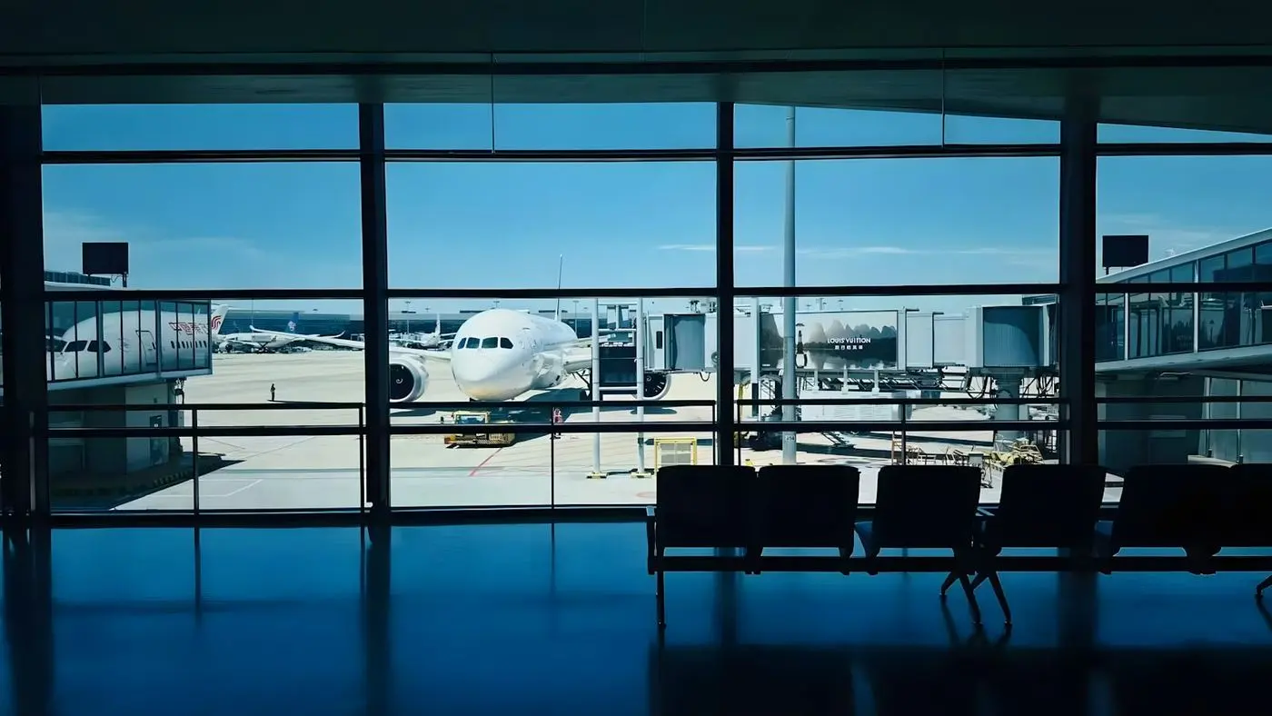 An airport departure gate seen through the terminal window